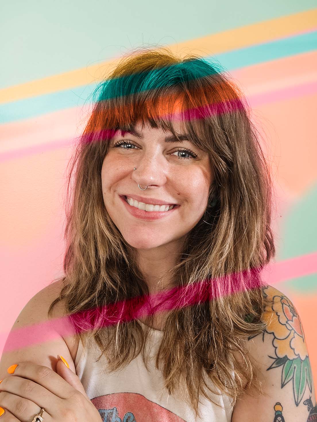 white woman with long hair and bangs smiling, pink streaks photoshopped across her face and colorful background