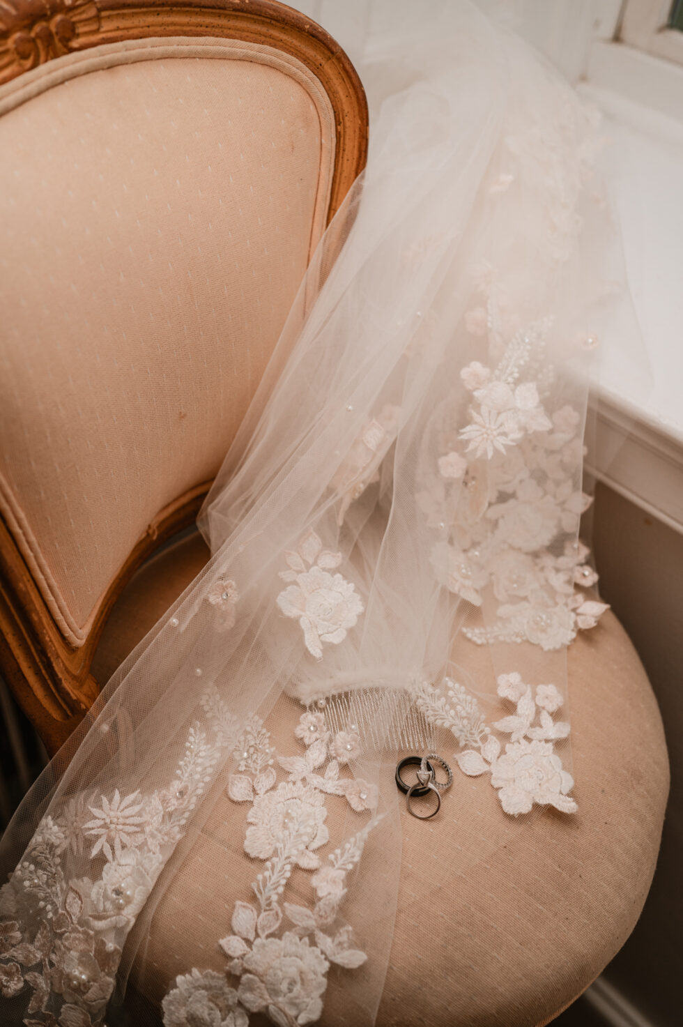 a lace veil draped across a chair with wedding rings sitting on top