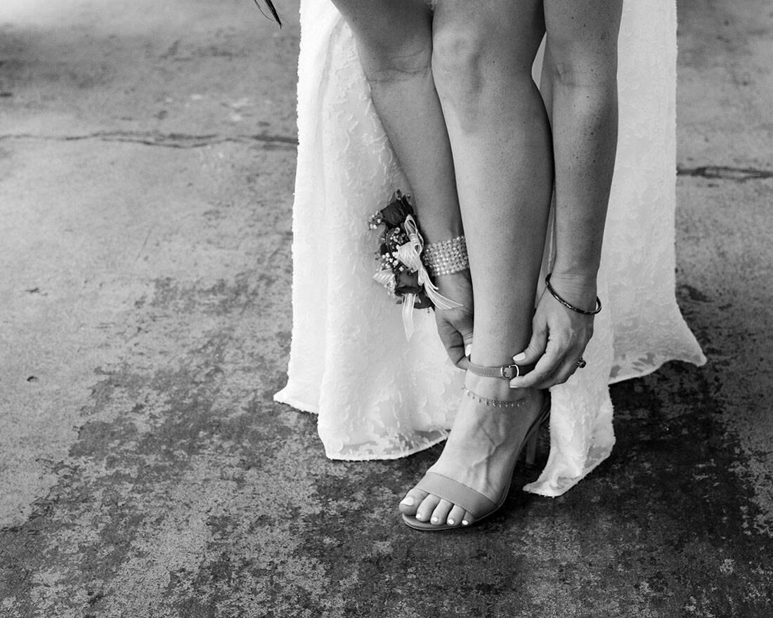 close up of bride putting on shoes in black and white