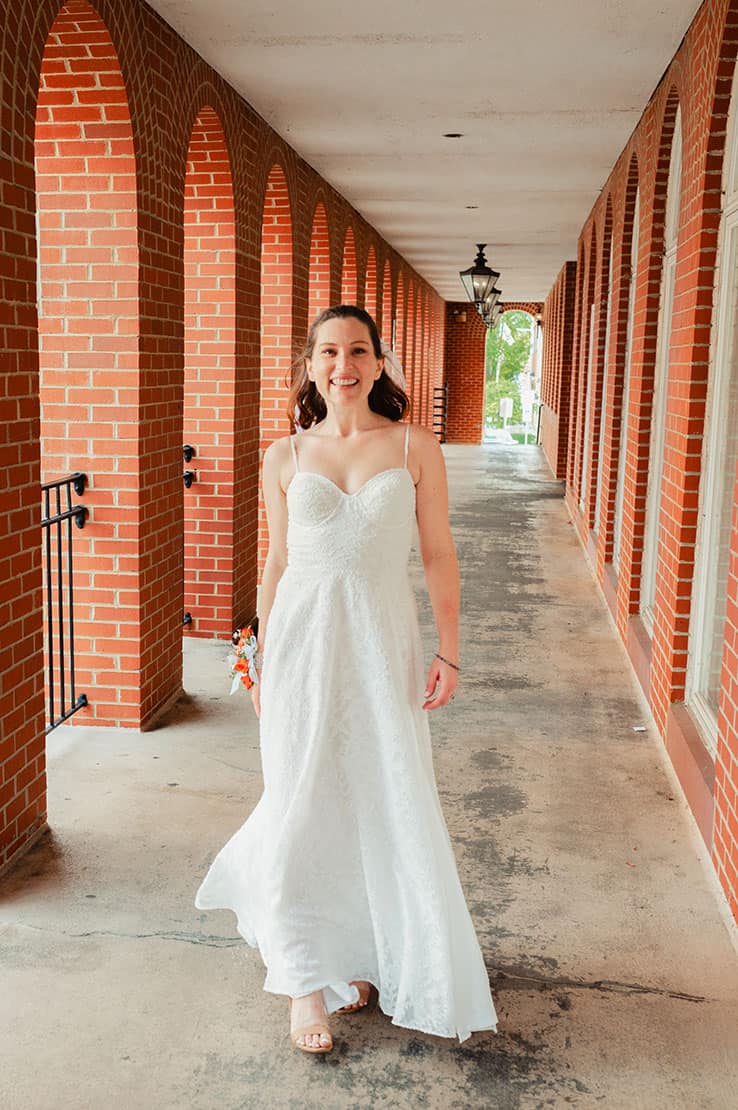 bride walking outside near brick wall