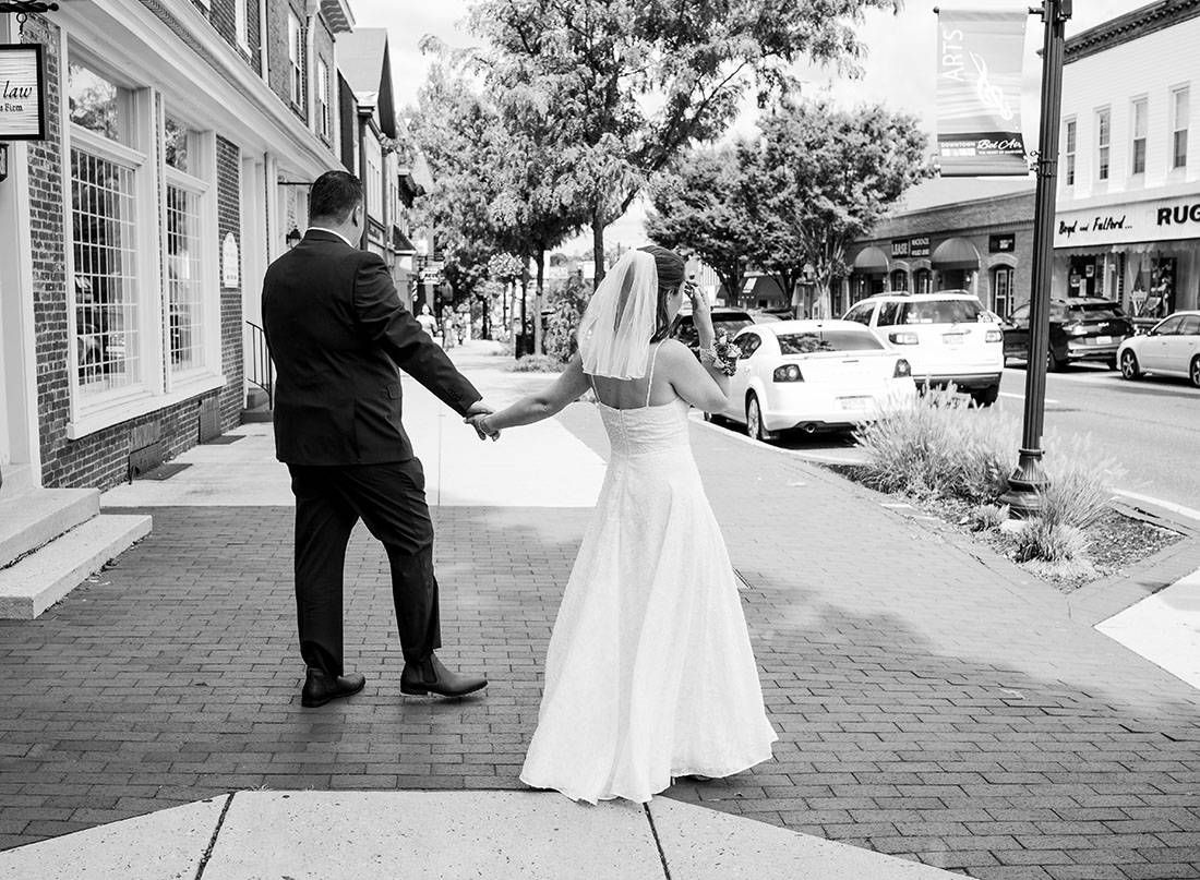 black and white photo of bride and groom crossing the street