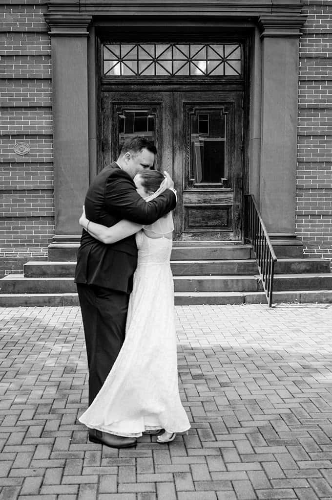 black and white photo of bride and groom hugging outside