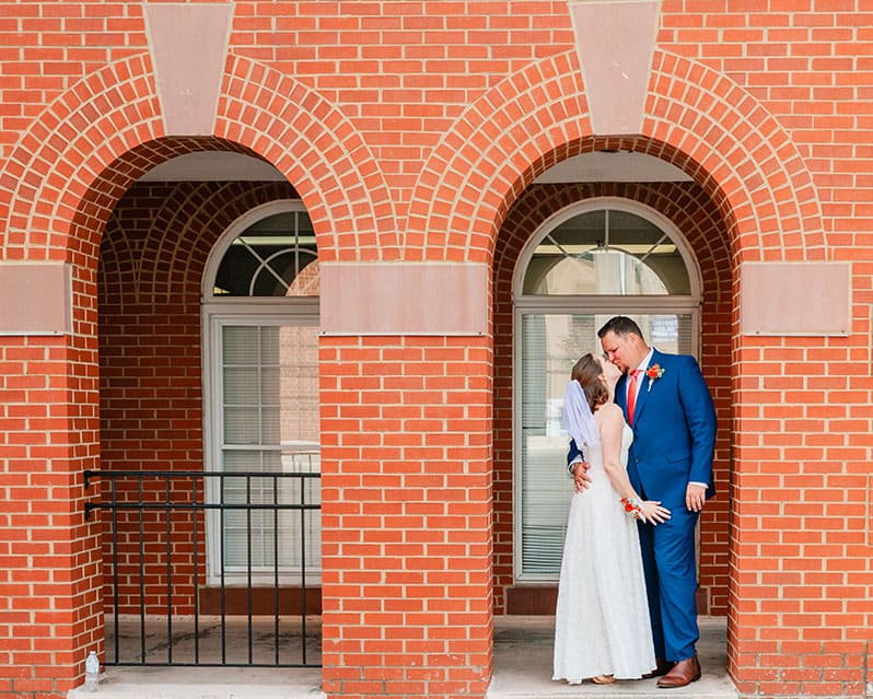 bride and groom standing in brick archway