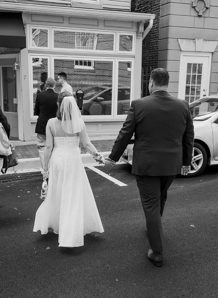 black and white photo of bride and groom walking to courthouse