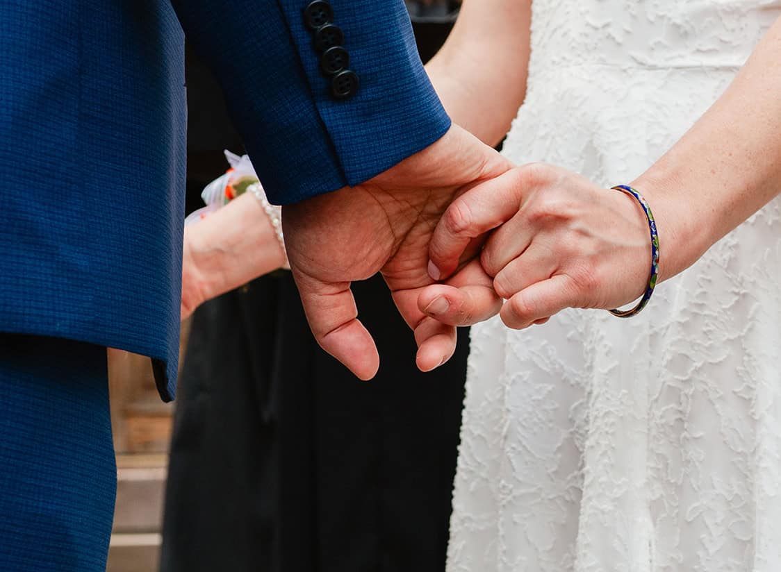 close up of bride and groom holding hands during wedding ceremony