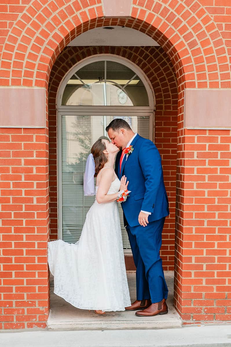 bride and groom kissing in brick archway